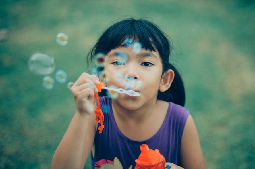 child sitting and blowing bubbles