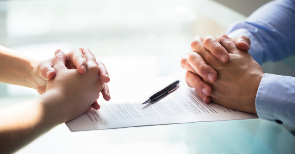 alimony paperwork resting on table between two pairs of hands